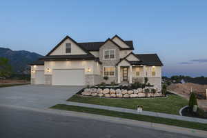 View of front of home featuring stone siding, board and batten siding, a front lawn, concrete driveway, and covered porch