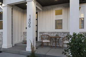View of exterior entry featuring stone siding, board and batten siding, and covered porch