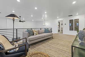 Living room with carpet flooring, a ceiling fan, and a chandelier