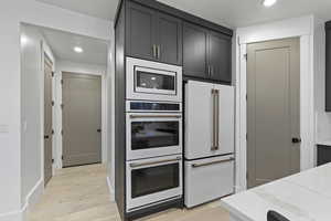 Kitchen featuring recessed lighting, white appliances, light wood-style flooring, and light stone countertops