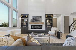 Living room featuring a high ceiling, wood finished floors, a large fireplace, and built in features