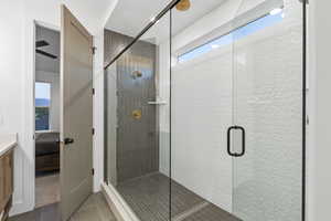 Ensuite bathroom featuring healthy amount of natural light, a stall shower, tile patterned flooring, and vanity