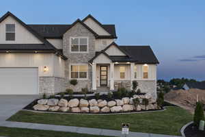 Modern farmhouse featuring board and batten siding, stone siding, and a front lawn