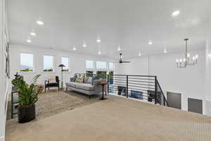 Living area featuring a ceiling fan, carpet floors, healthy amount of natural light, and suspended lighting