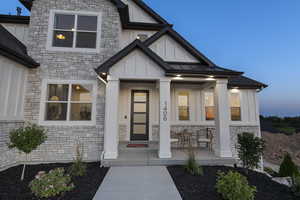 Property entrance featuring stone siding, a porch, board and batten siding, and a standing seam roof