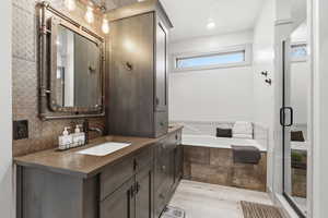 Maser bath with vanity, light wood finished floors, a bath, a stall shower, and recessed lighting