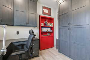 Home office with light wood finished floors.  Enter through the hidden door.