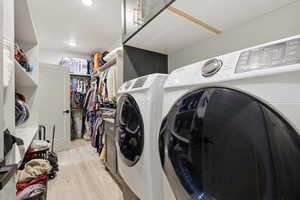 Master Bedroom Closet and Laundry area with light wood finished floors, cabinet space, and washer and dryer