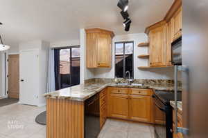 Kitchen with rail lighting, black appliances, a peninsula, light tile patterned floors, and open shelves