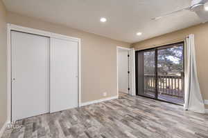 Unfurnished bedroom with access to exterior, a closet, light wood-style flooring, and recessed lighting
