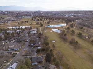 Aerial view of property and surrounding area featuring a water and mountain view, a local golf course, and nearby suburban area