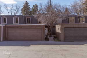 Front facade with mansard roof, a shingled roof, and concrete driveway