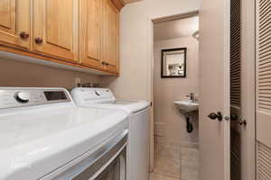 Laundry area with washing machine and clothes dryer, light tile patterned floors, and cabinet space