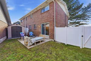 Rear view of house featuring a shed, a gate, brick siding, a patio, and outdoor seating