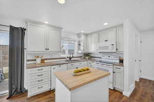 Kitchen featuring white cabinets, butcher block countertops, backsplash, and recessed lighting