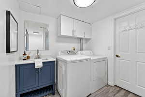 Laundry room and full bathroom with independent washer and dryer, light wood finished floors, and cabinet space