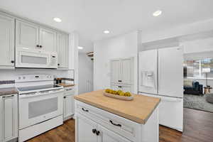 Kitchen featuring white appliances, wooden counters, white cabinetry, and decorative backsplash