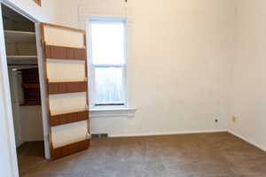 Unfurnished bedroom with dark carpet and baseboards