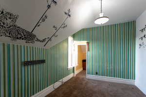Hall with wallpapered walls, carpet, and lofted ceiling