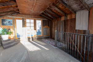 Interior space with lofted ceiling, carpet floors, and wooden walls