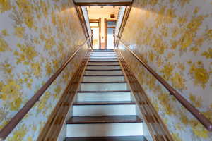 Stairs featuring wallpapered walls