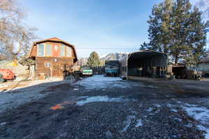 View of outdoor structure with a carport, dirt driveway, and a mountain view