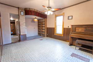 Living room featuring wood walls, ceiling fan, and a wainscoted wall