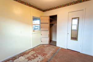 Unfurnished bedroom featuring multiple windows and a closet