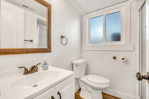 Full bath with vanity, a shower with shower door, and wood finished floors