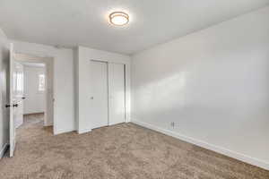 Unfurnished bedroom with carpet floors, a closet, and a textured ceiling