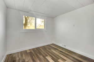 Empty room featuring dark wood-style flooring and baseboards