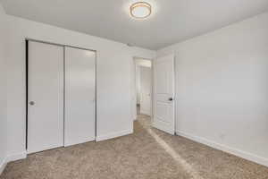 Unfurnished bedroom featuring a closet, light colored carpet, and a textured ceiling