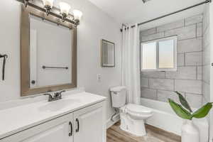 Full bath featuring shower / bath combo with shower curtain, vanity, and light wood finished floors