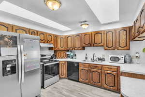 Kitchen featuring stainless steel appliances, wood finish cabinets, and light wood finished floors