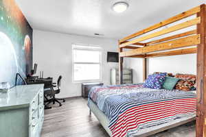 Bedroom featuring a desk, wood finished floors, and a textured ceiling