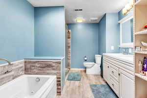 Bathroom featuring vanity, a jetted tub, a textured ceiling, light wood-style floors, and a shower stall