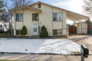 Split foyer home featuring a storage unit, an attached carport, and concrete driveway
