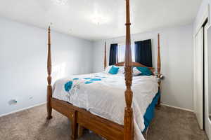 Bedroom with a textured ceiling, carpet, and a closet