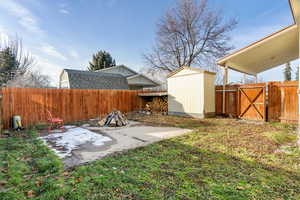 Fenced backyard with a gate, a storage unit, and a patio