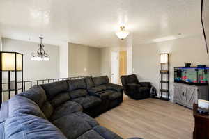 Living room with a textured ceiling, hanging lights, and light wood-style flooring