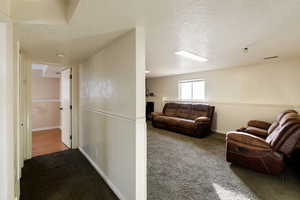 Corridor with dark carpet, a textured ceiling, and a wainscoted wall