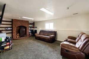 Living room featuring a wood stove, wainscoting, carpet floors, and a textured ceiling