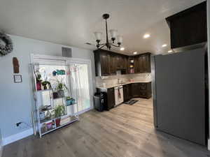 Kitchen with freestanding refrigerator, dark wood finish cabinetry, glass insert cabinets, decorative backsplash, and light wood-style flooring