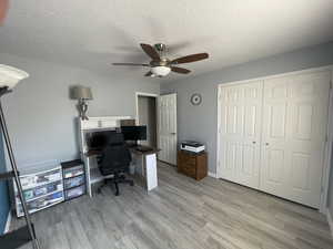 Home office featuring light wood-type flooring, a textured ceiling, and ceiling fan