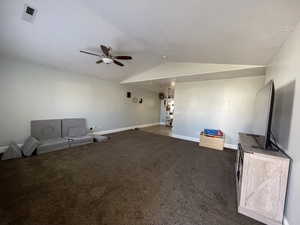 Unfurnished living room featuring ceiling fan and dark carpet