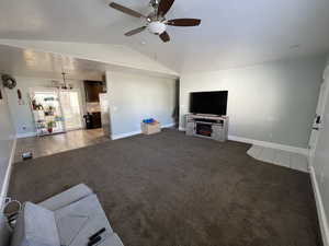 Unfurnished living room featuring a ceiling fan, light carpet, and a lit fireplace