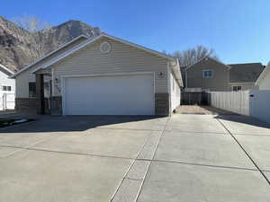 View of front of home with concrete driveway, an attached garage, a gate, and stone siding