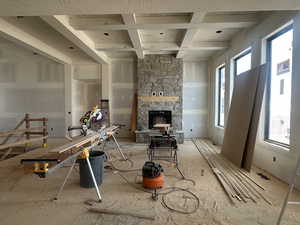 Living area featuring coffered ceiling and a stone fireplace