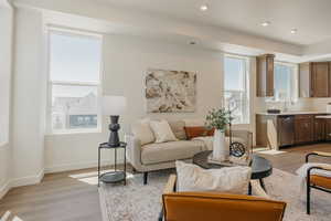 Living area with light wood-type flooring and recessed lighting