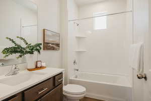 Bathroom featuring vanity, bathtub / shower combination, and dark wood-type flooring